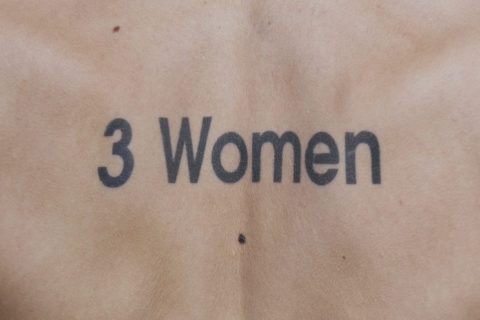 tattoo on a person's back saying "3 women"